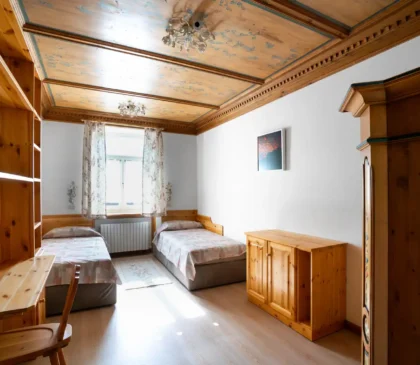 Camera a due letti con mobili in legno e armadio decorato a mano nell’appartamento a Cortina